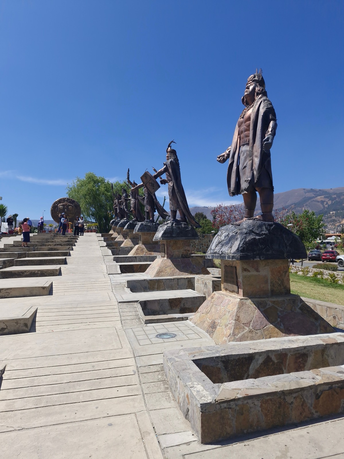 The avenue of carved Inca ruler statues on their plinths, climbing a stepped promenade
