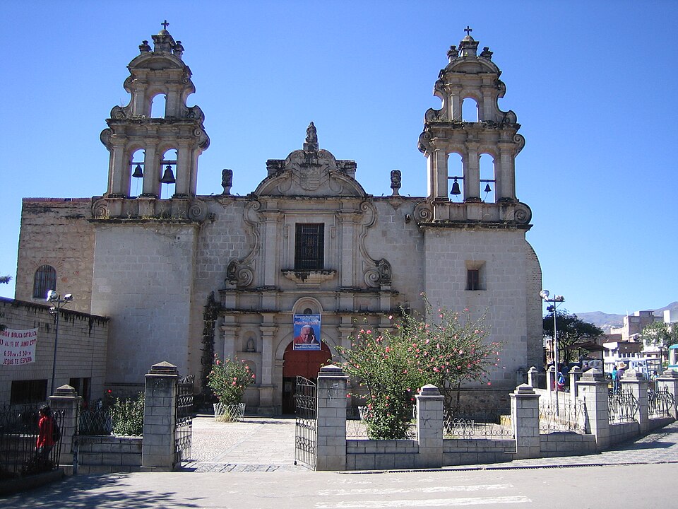 The twin bell towers and white stone front of La Recoleta behind its railings on a clear day