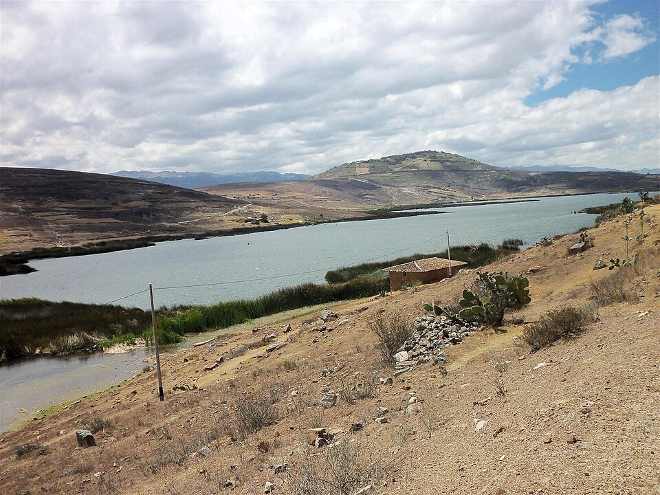 Laguna San Nicolás under a pale sky, dry hills running down to the far shore