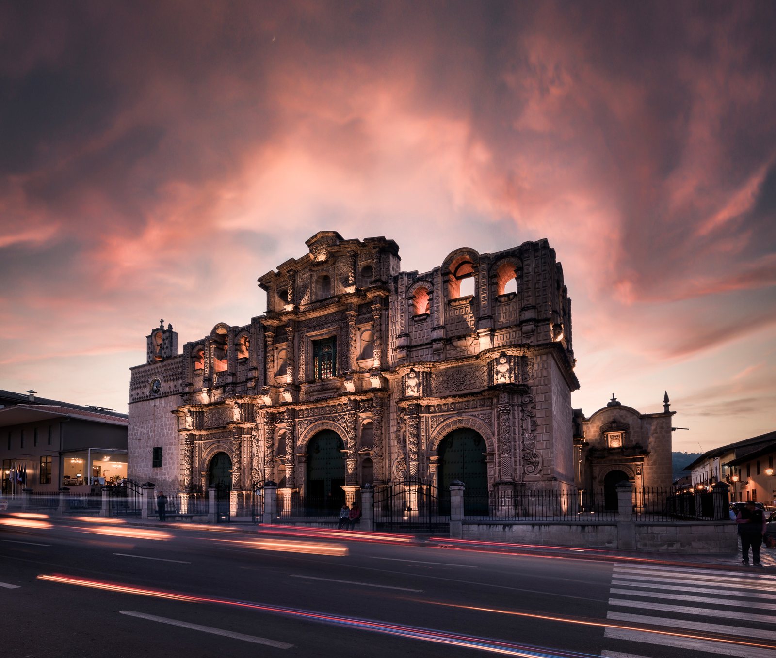 The carved baroque front of Cajamarca cathedral against a pink and grey sky at dusk
